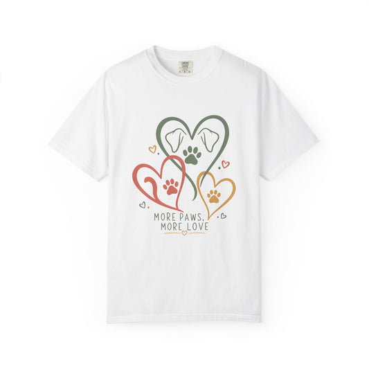 A white short-sleeve crewneck t-shirt featuring a graphic of three interlocking hearts in green, red, and orange, each containing a dog silhouette and paw print, with the text 'MORE PAWS, MORE LOVE' printed below.