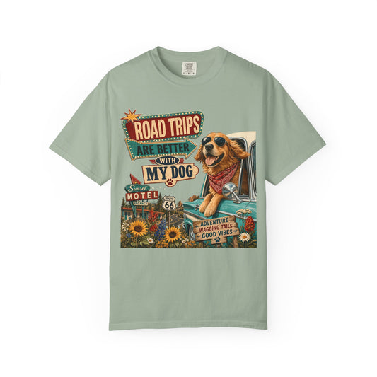 A sage green crewneck t-shirt featuring a colorful graphic print of a golden retriever dog driving a vintage car with retro-style road trip signs that read 'ROAD TRIPS ARE BETTER WITH MY DOG'.