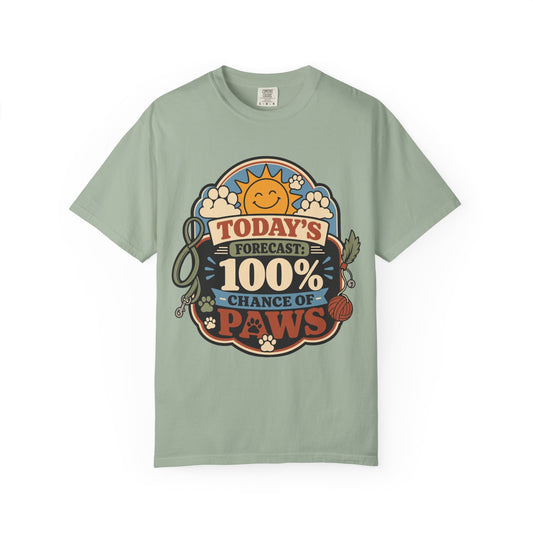 A sage green crewneck t-shirt featuring a colorful graphic print on the front with a cartoon sun, paw prints, and the text 'TODAY'S FORECAST: 100% CHANCE OF PAWS'.