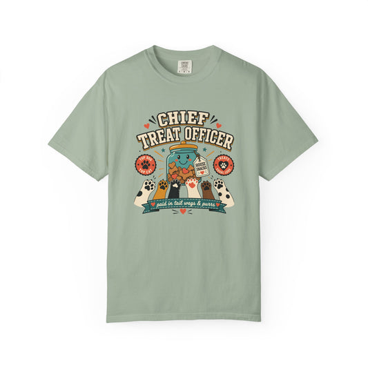 A sage green short-sleeve t-shirt with a colorful retro graphic on the chest that reads 'CHIEF TREAT OFFICER' above an illustration of a jar of pet treats and treats being shared with dogs and cats.