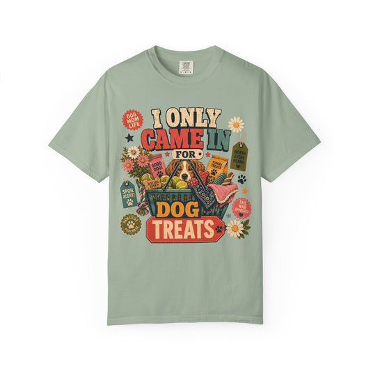 A sage green short-sleeve t-shirt with a colorful graphic print on the front that reads 'I ONLY CAME IN FOR DOG TREATS' surrounded by illustrations of dog treats, a dog, flowers, and tags.