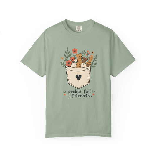 A sage green short-sleeve t-shirt with a graphic of a pocket filled with treats and small animals, with the text 'packet full of treats' printed below, shown on a plain white background.