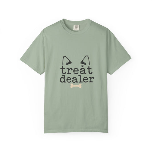 A sage green short-sleeve crewneck t-shirt featuring a black graphic of cat ears and the words 'treat dealer' with a small bone underneath, displayed on a clean white background.